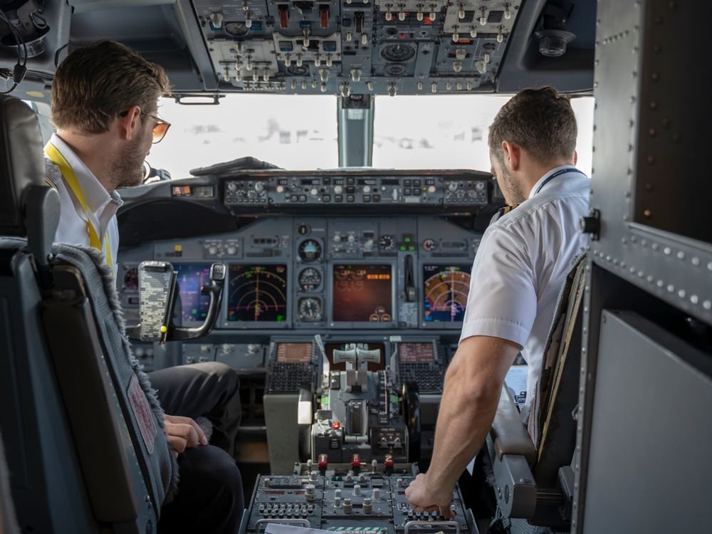 Two airline pilots in a cockpit running through pre-flight checks, representing the aviation English assessment candidates prepare for