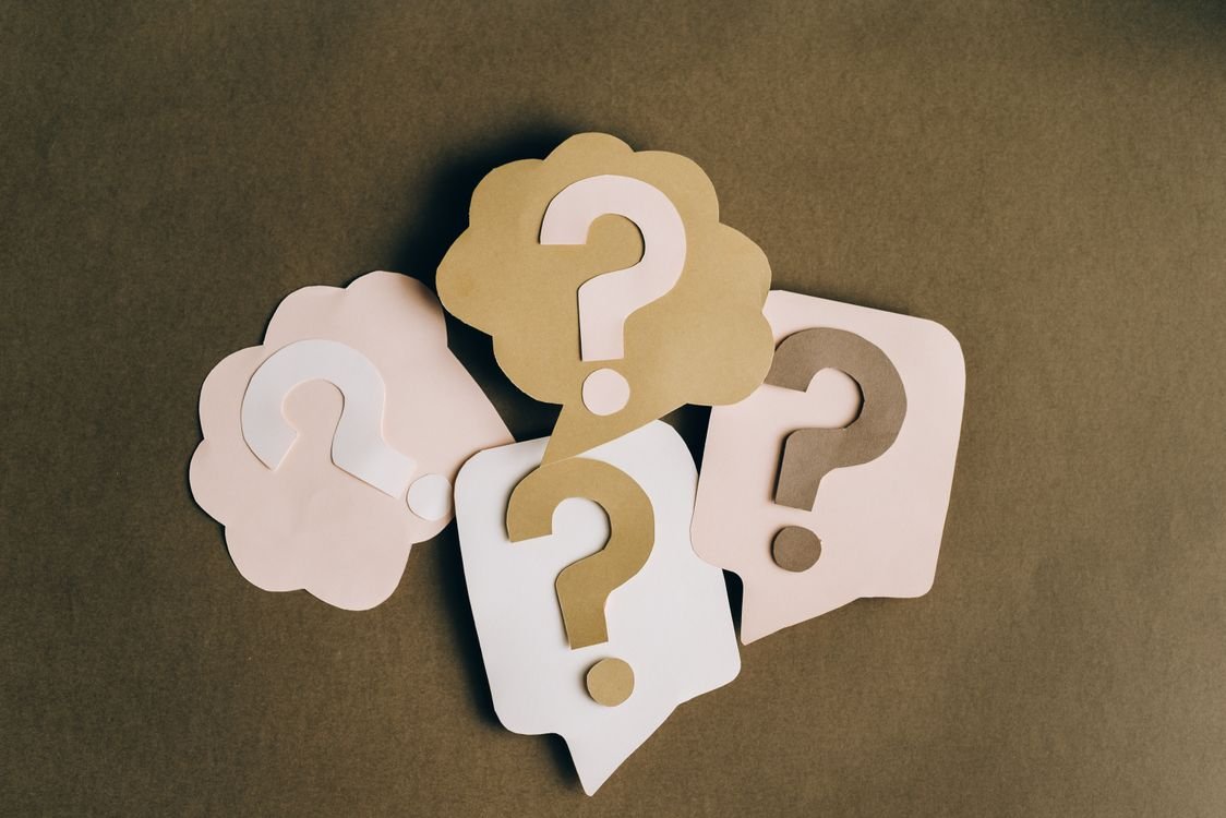 Paper cut-out speech bubbles with question marks, representing the key questions to ask when choosing a one-to-one English tutor