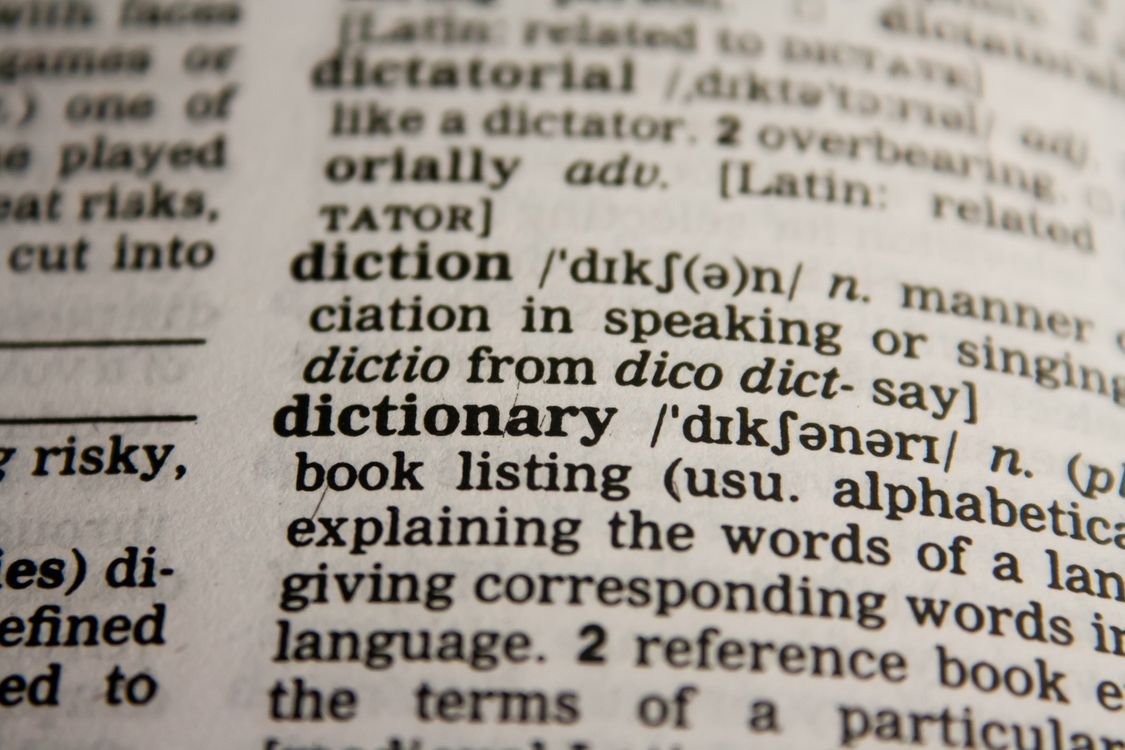 A close-up of an open dictionary page showing the word dictionary and its definition with phonetic spelling