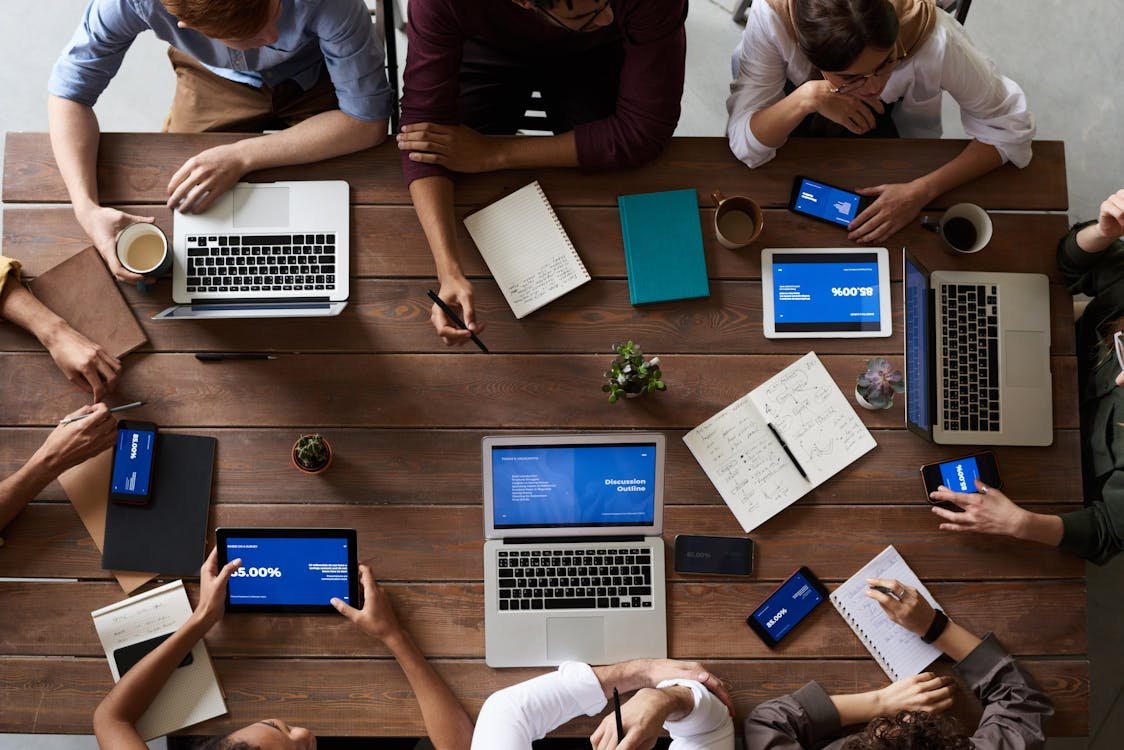 Startup founders collaborating around a laptop in a bright open-plan office, discussing plans in English