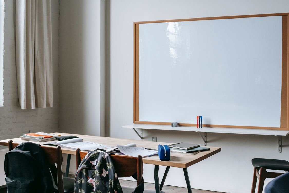 An English classroom desk with open notebooks and study materials in front of a whiteboard, representing everyday English study and practice