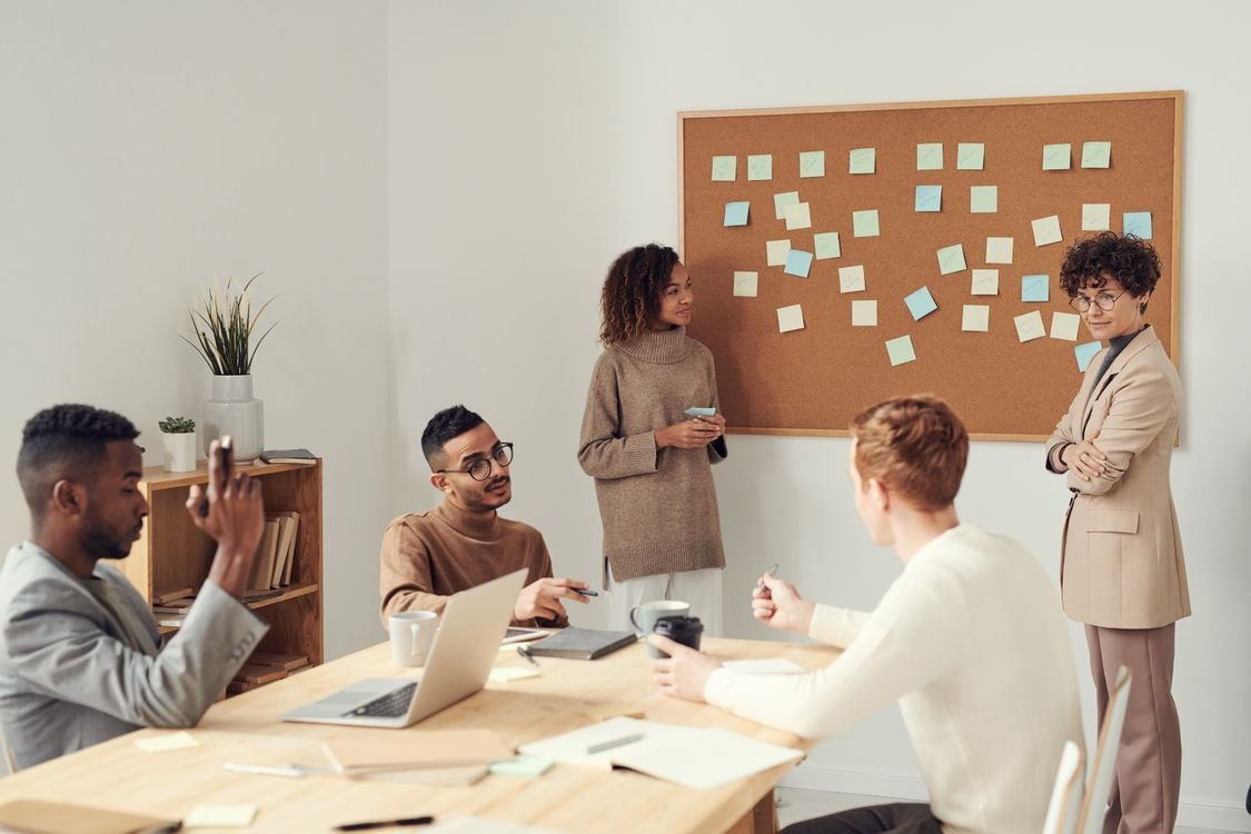 A group of colleagues in discussion, one person speaking while the others listen, illustrating how we report what someone said in English