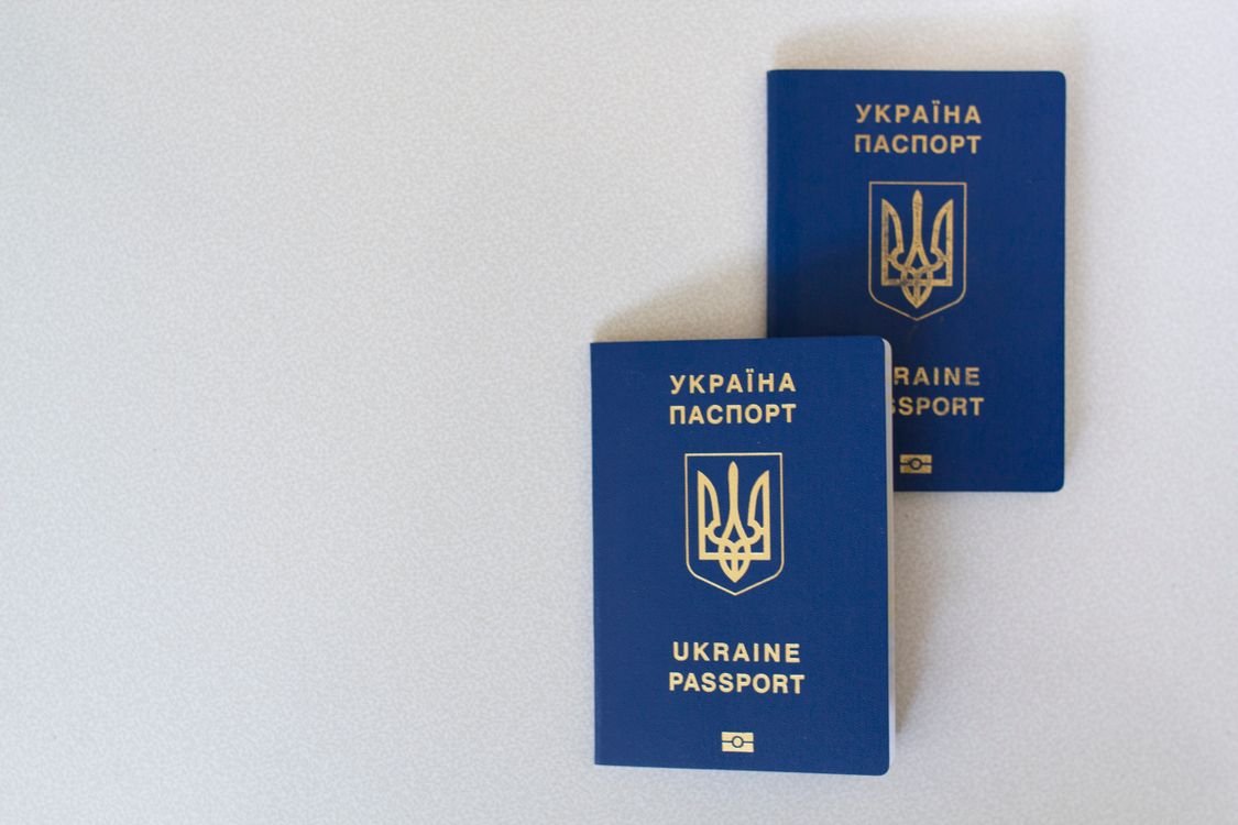 Two blue biometric passports lying on a plain light grey background