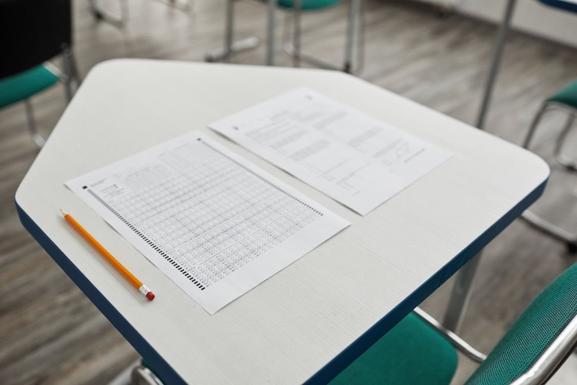 IELTS candidate building vocabulary lists from study books and notes at a desk