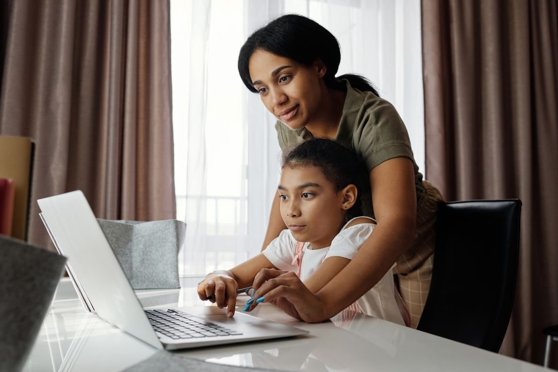 An adult learner in a one-to-one online English lesson with a tutor on a laptop video call at home