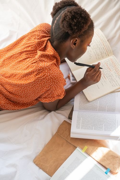 An adult English learner absorbed in reading and taking notes from a book, studying advanced English at C1 proficient-user level
