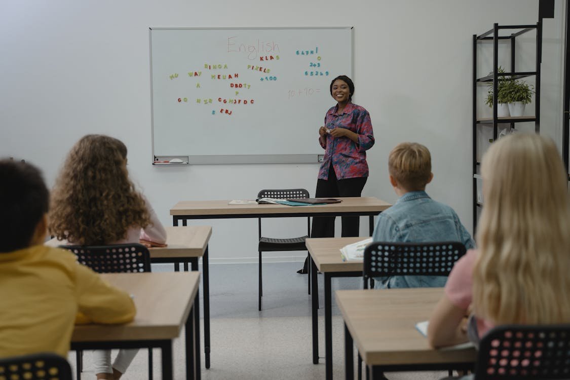 Teacher smiling at a small group of English language students in a classroom